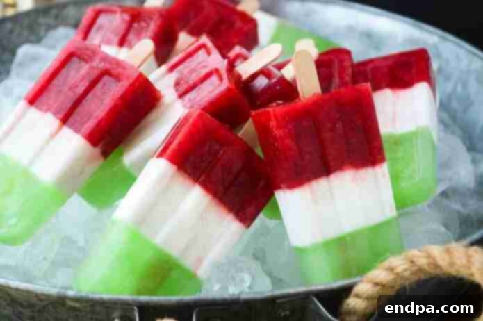 Layered Cinco de Mayo popsicles in red, white, and green, featuring fresh strawberry, coconut, and lime flavors.