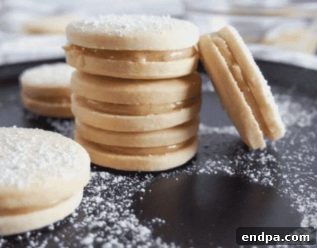Delicate Dulce de Leche Sandwich Cookies (Alfajores), dusted with powdered sugar and filled with caramel.