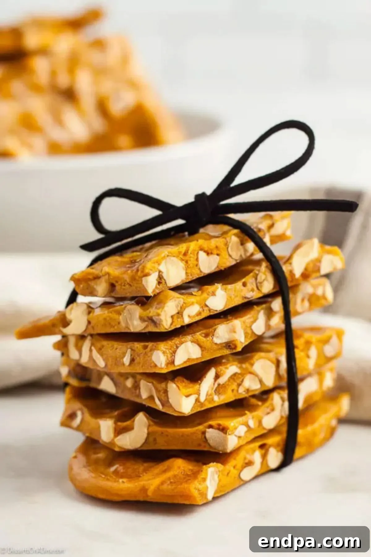 Peanut brittle pieces elegantly stacked and tied with a festive bow, ready for gifting.