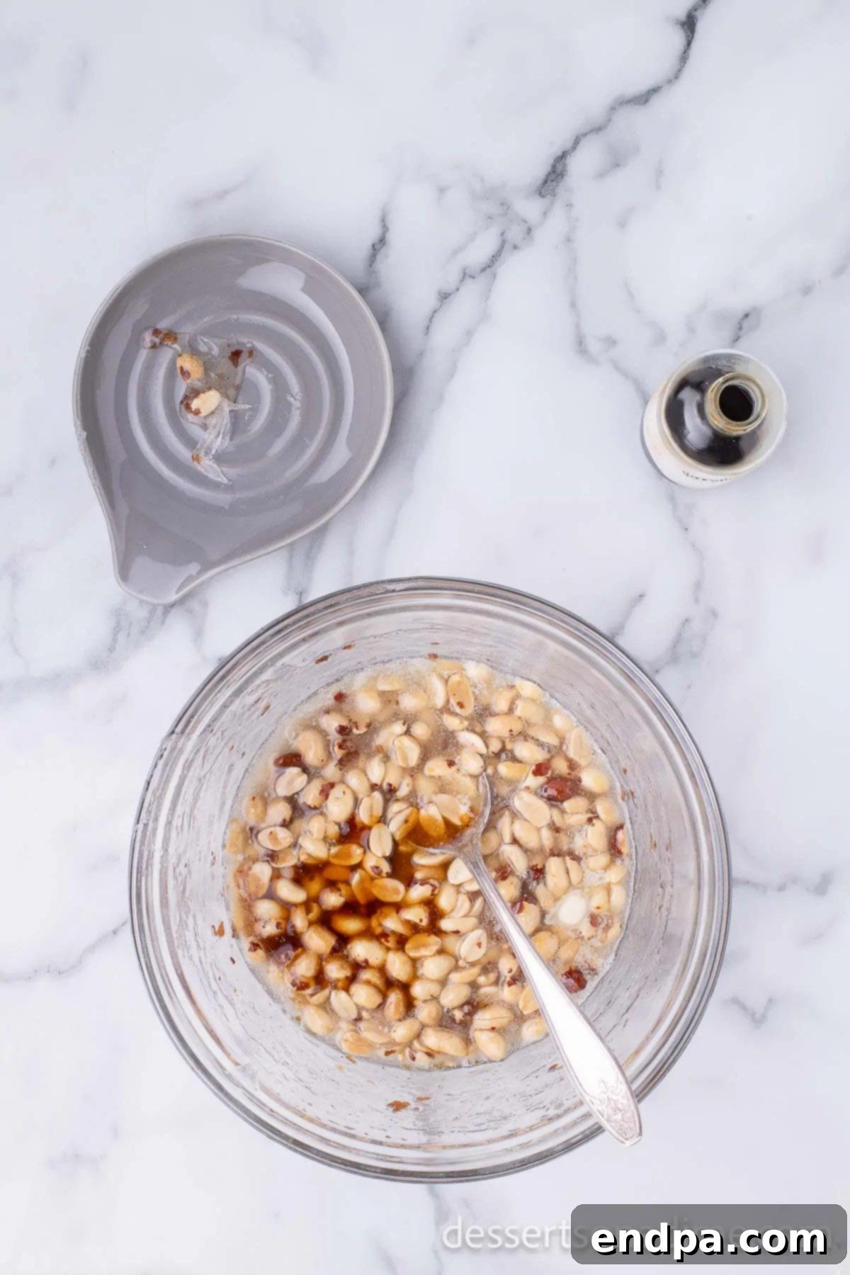 Melted butter and vanilla extract being stirred into the hot brittle mixture.