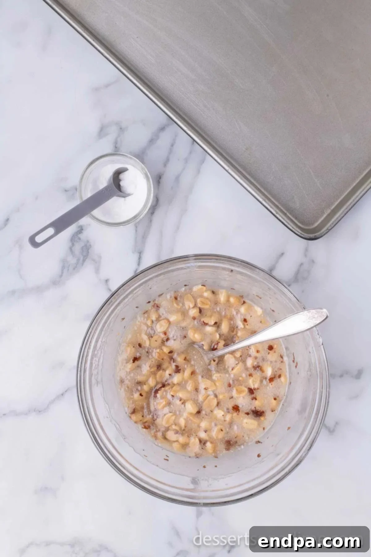 Baking soda being stirred into the foamy, hot peanut brittle mixture.