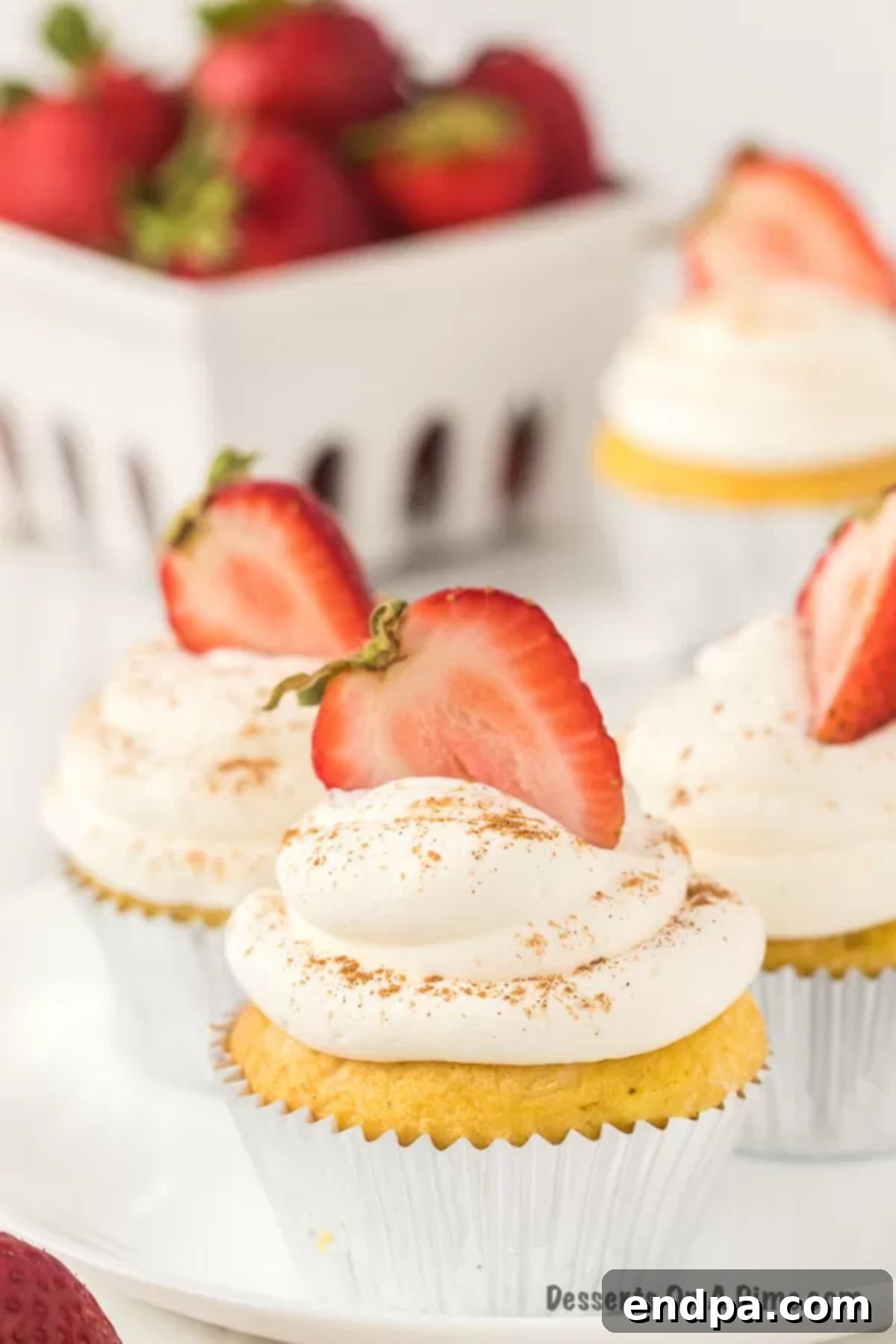 Close up image of Tres Leche Cupcakes topped with slice strawberries. 