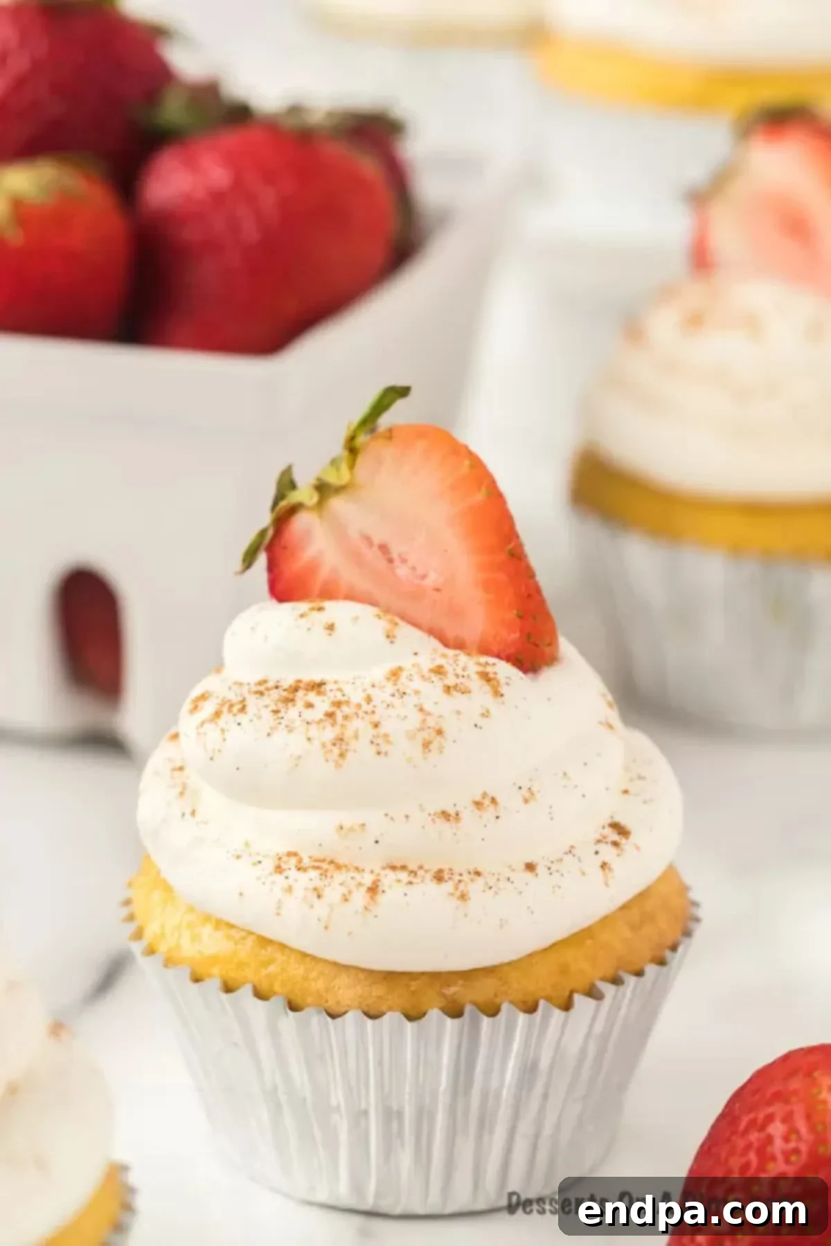 Close up image of Tres Leche Cupcakes topped with slice strawberries. 