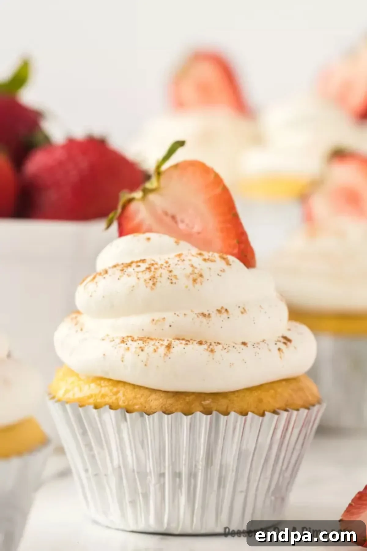 Close up image of Tres Leche Cupcakes topped with slice strawberries. 