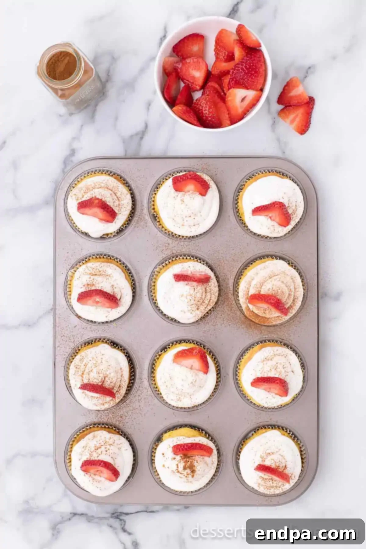 Cupcakes topped with whipped cream and strawberries. 