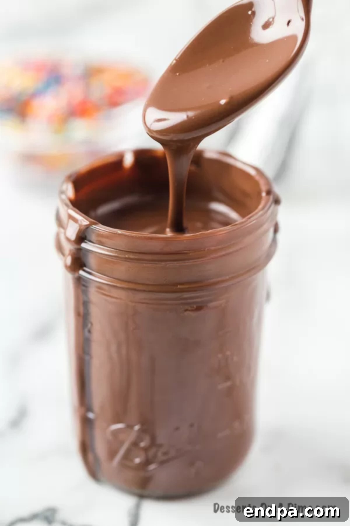 Homemade Hardening Chocolate Topping 6 Homemade Magic Shell in a jar with a spoon, ready for use.