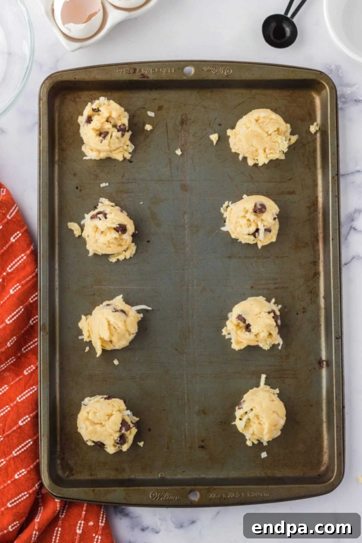 Chewy Coconut Chocolate Chip Dreams 8 Uniform cookie dough balls placed on a baking sheet lined with parchment paper.