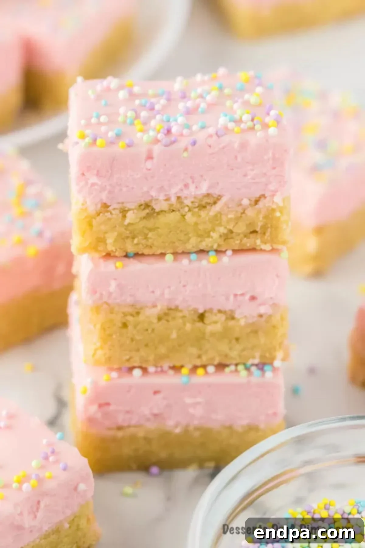 Perfectly Soft Sugar Cookie Bars 2 Stacked sugar cookie bars with vibrant pink frosting and colorful sprinkles