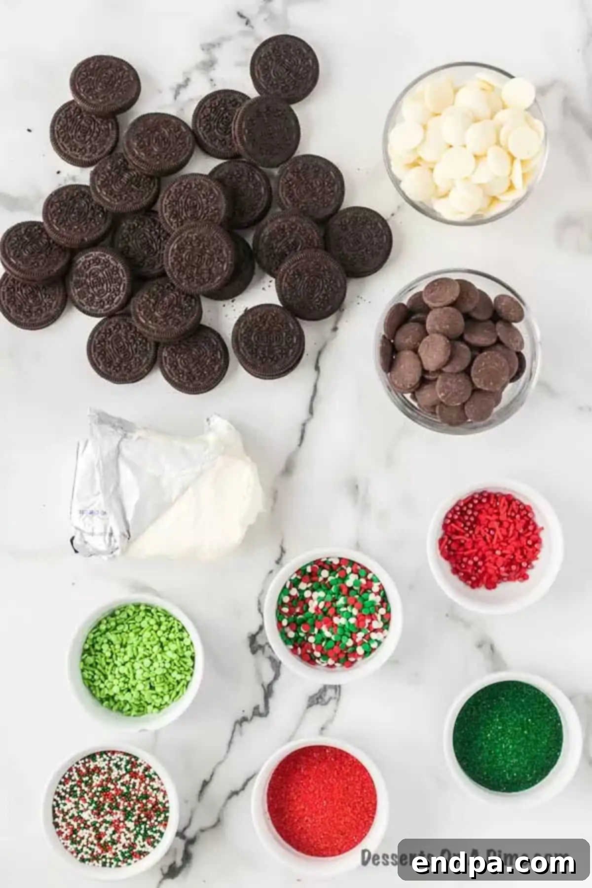 Irresistible Holiday Oreo Truffles 3 A flat lay photograph showcasing the simple ingredients for Christmas Oreo Balls: a package of Oreo cookies, a block of cream cheese, a bowl of melting wafers, and a container of festive Christmas sprinkles.