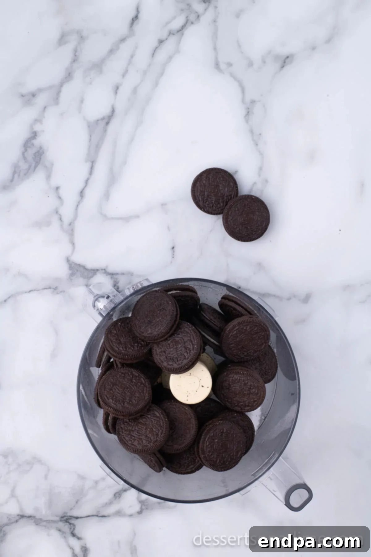 Irresistible Holiday Oreo Truffles 4 Oreo cookies being crushed in a food processor, transforming into fine, dark crumbs.