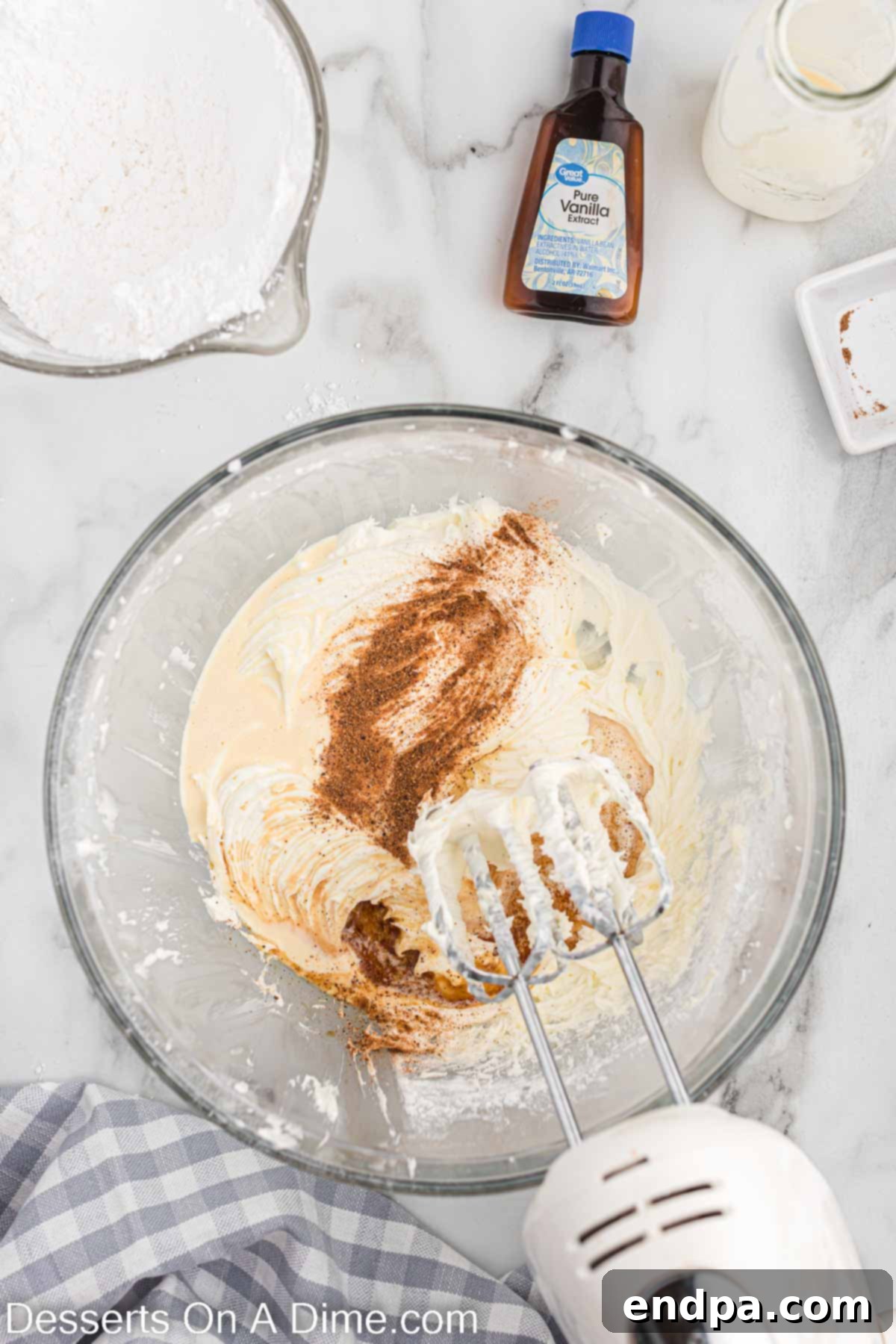 Festive Eggnog Cupcakes 11 Eggnog, vanilla extract, and nutmeg added to the frosting mixture in a mixing bowl.