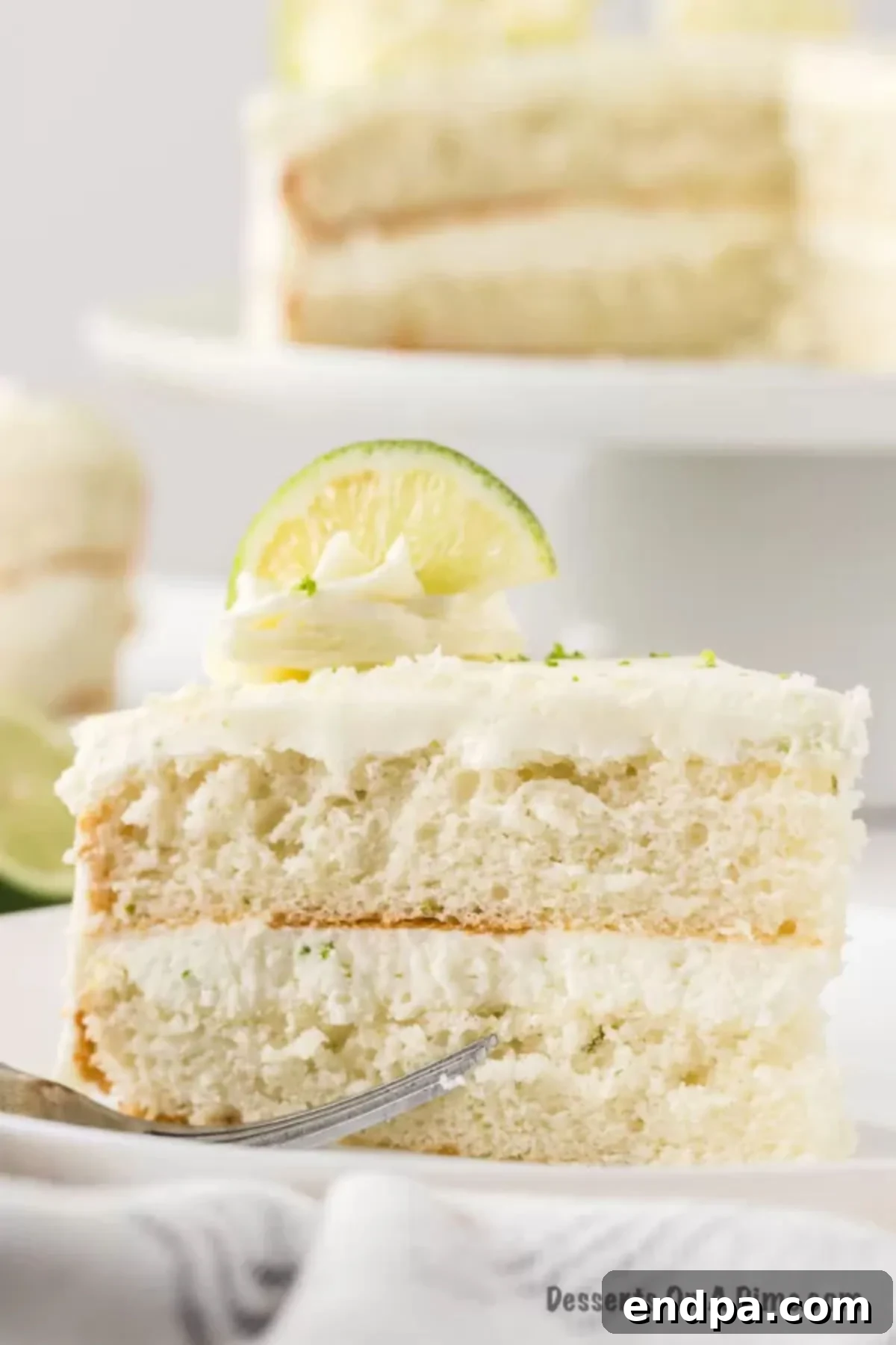 Close up photo of a slice of Margarita cake on a white plate, showing the layers and frosting.