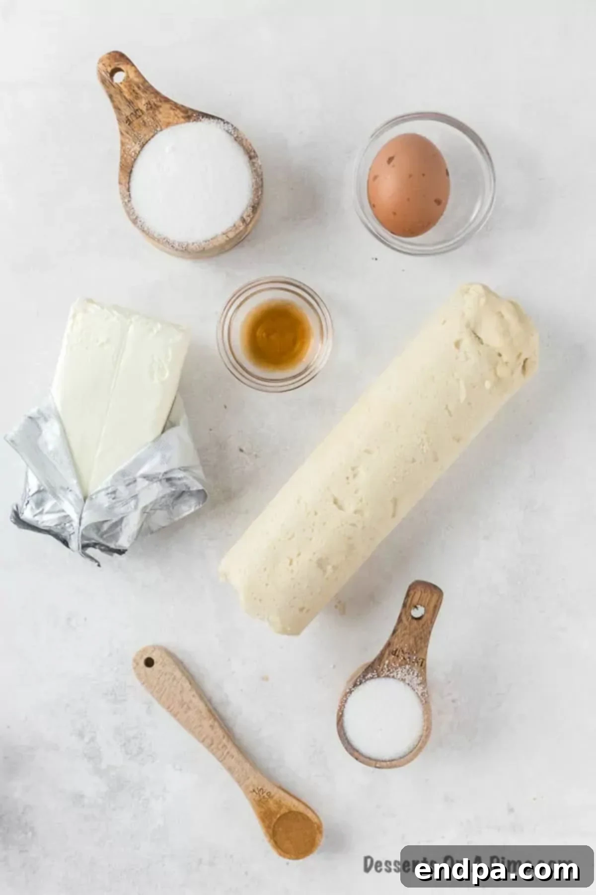 Irresistible Snickerdoodle Cheesecake Bars 3 Key ingredients for Snickerdoodle cheesecake bars laid out: pre-made sugar cookie dough, sugar, cinnamon, softened cream cheese, eggs, and vanilla extract.