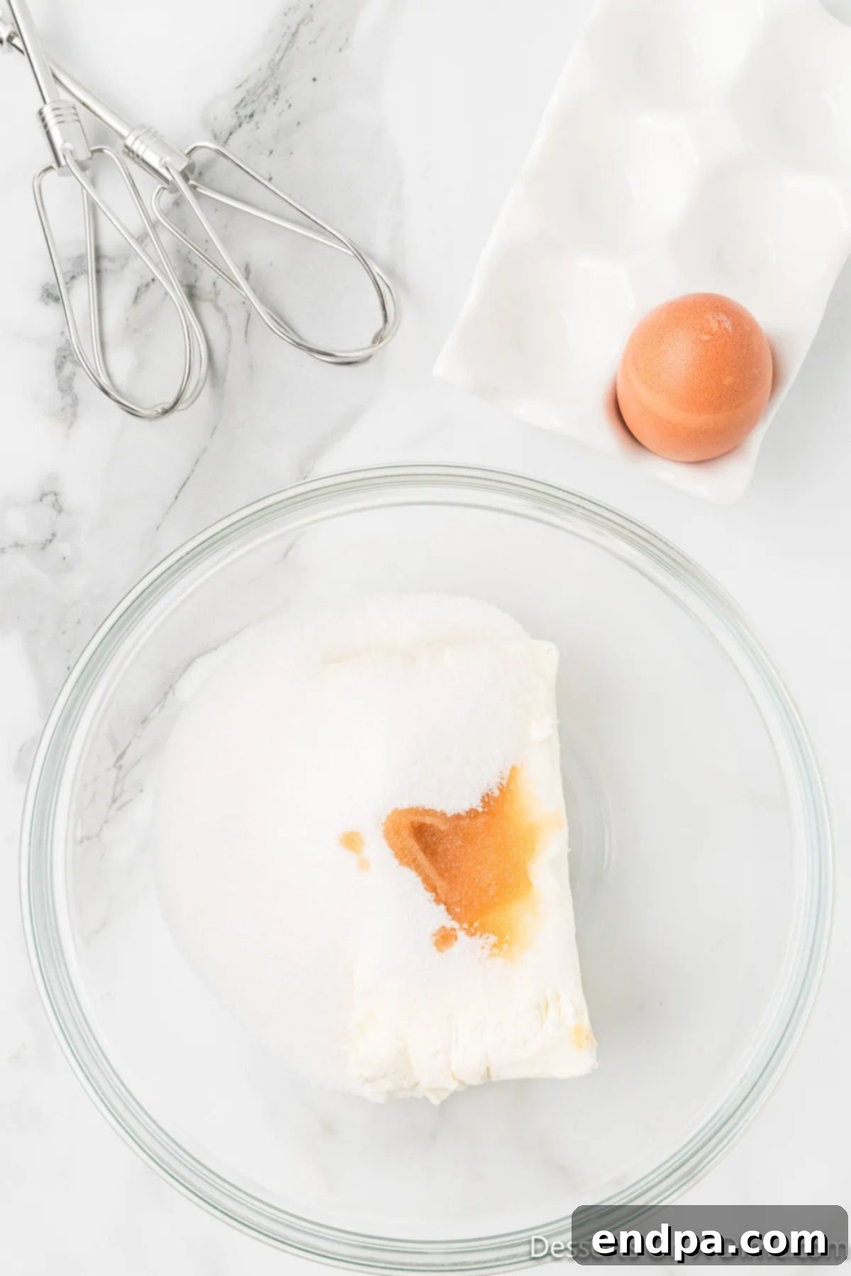 Irresistible Snickerdoodle Cheesecake Bars 4 Softened cream cheese, egg, and vanilla extract are combined in a mixing bowl, ready to be beaten into a smooth cheesecake batter.