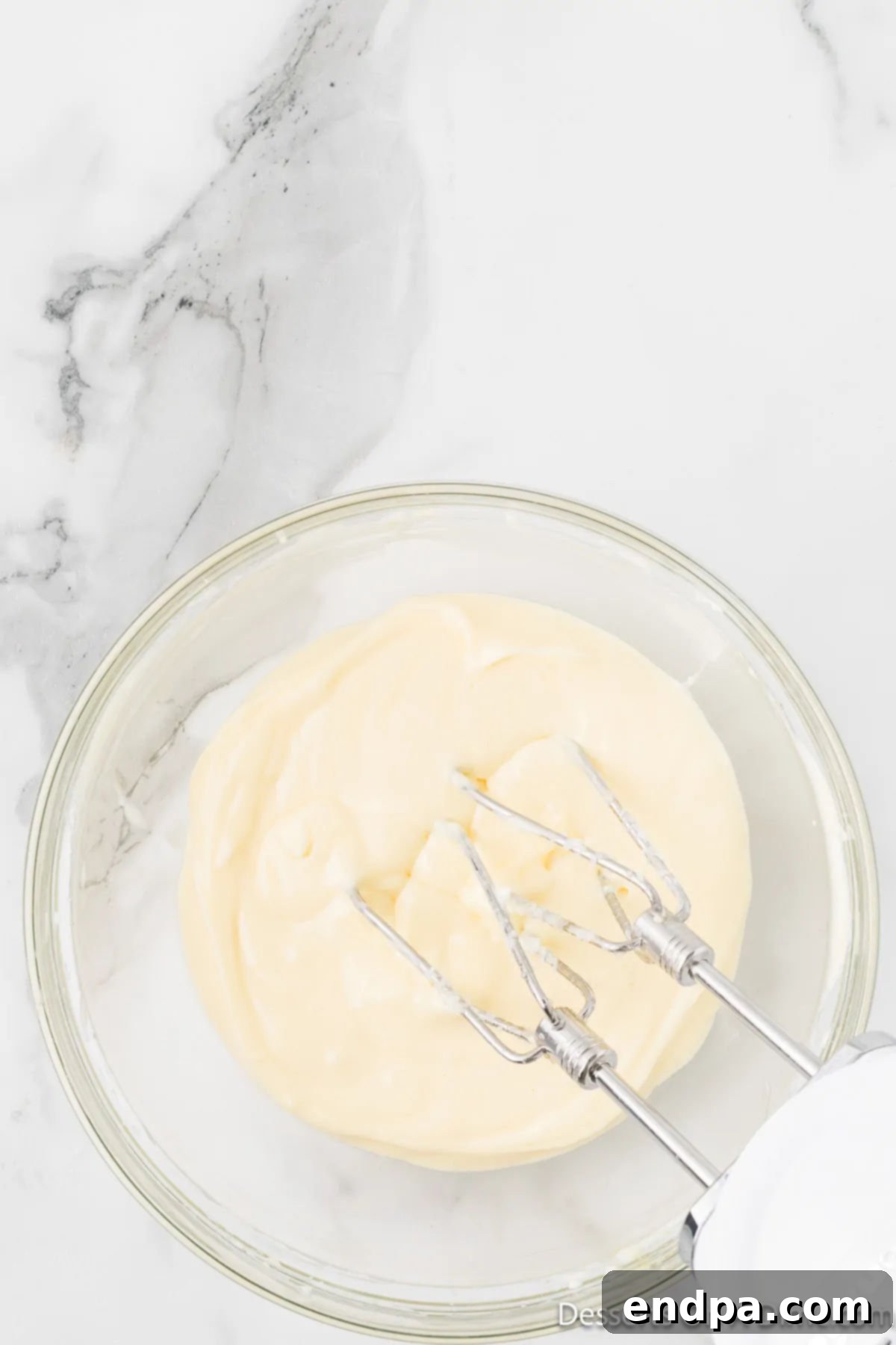 Irresistible Snickerdoodle Cheesecake Bars 5 The cheesecake mixture, now smooth and creamy after being beaten, fills a bowl and awaits its place atop the cookie crust.