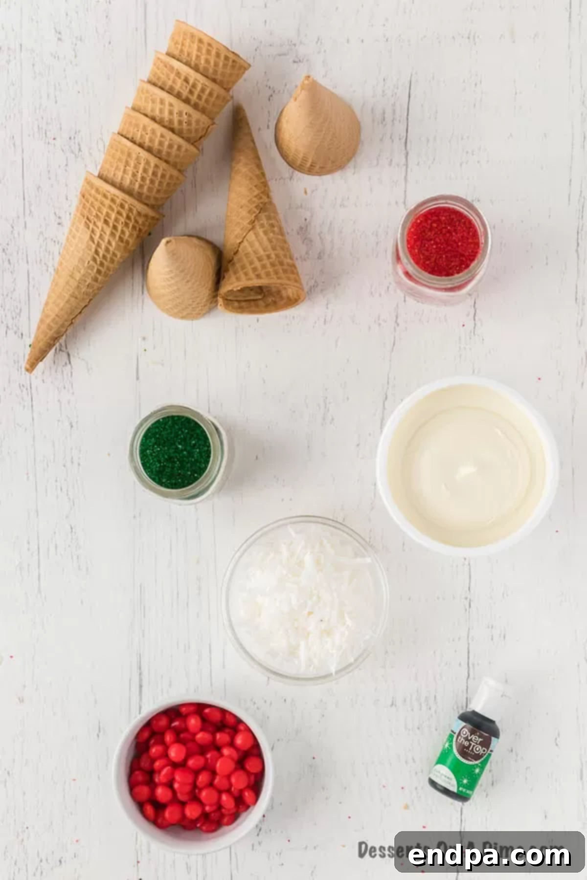 Ingredients laid out for Ice Cream Cone Christmas Trees, including frosting, food coloring, cones, and assorted candies.