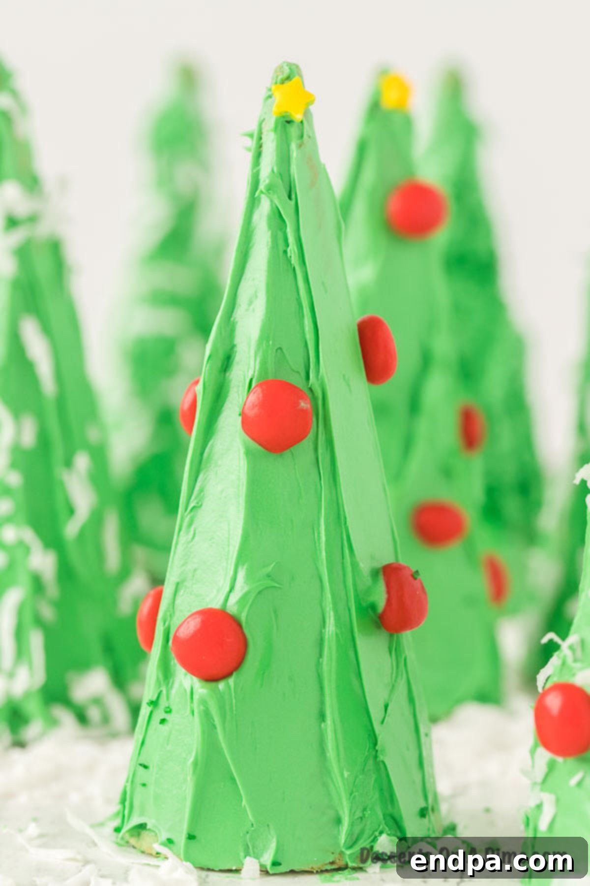 A cluster of beautifully decorated Ice Cream Cone Christmas Trees, showcasing various candy ornaments.