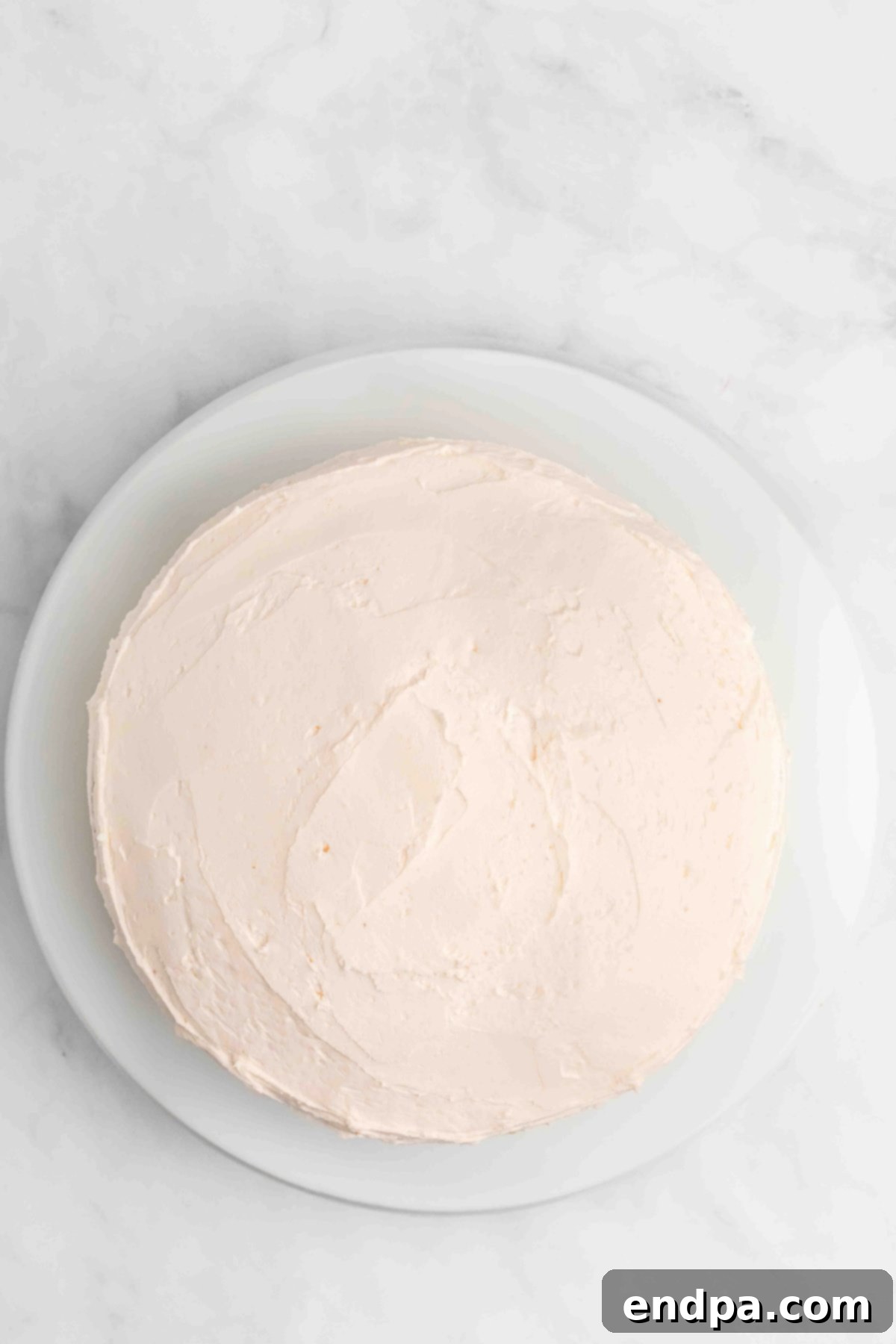 Cake on platter being frosted.