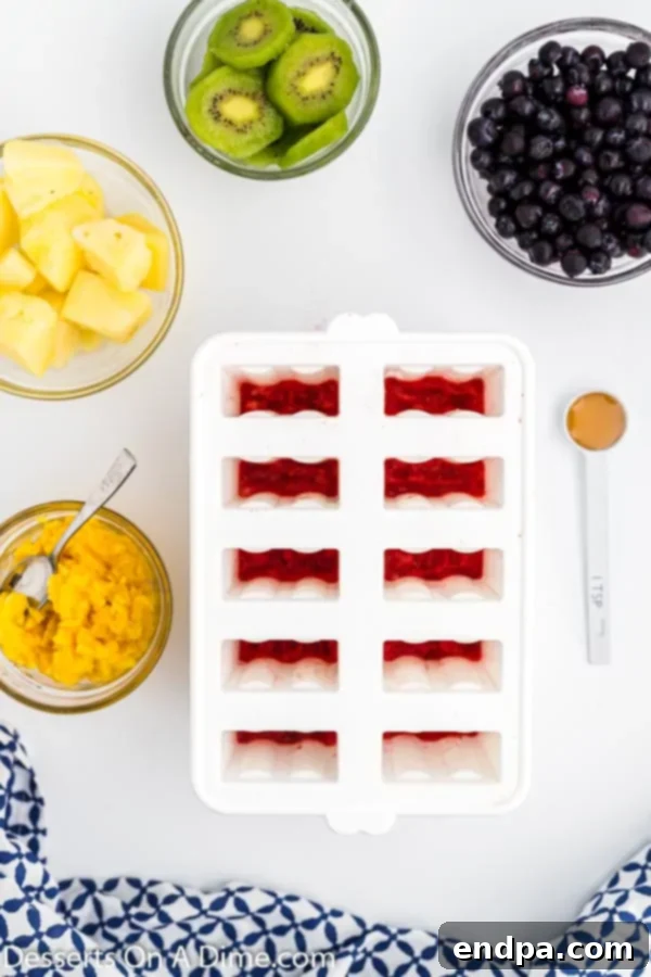 Frozen Rainbow Delights 4 Strawberry puree in popsicle molds, showing the first layer.
