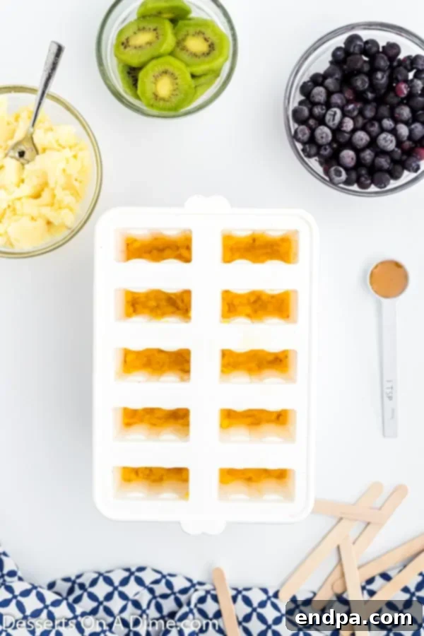 Frozen Rainbow Delights 5 Mango layer being added to the popsicle molds, on top of the strawberry layer.