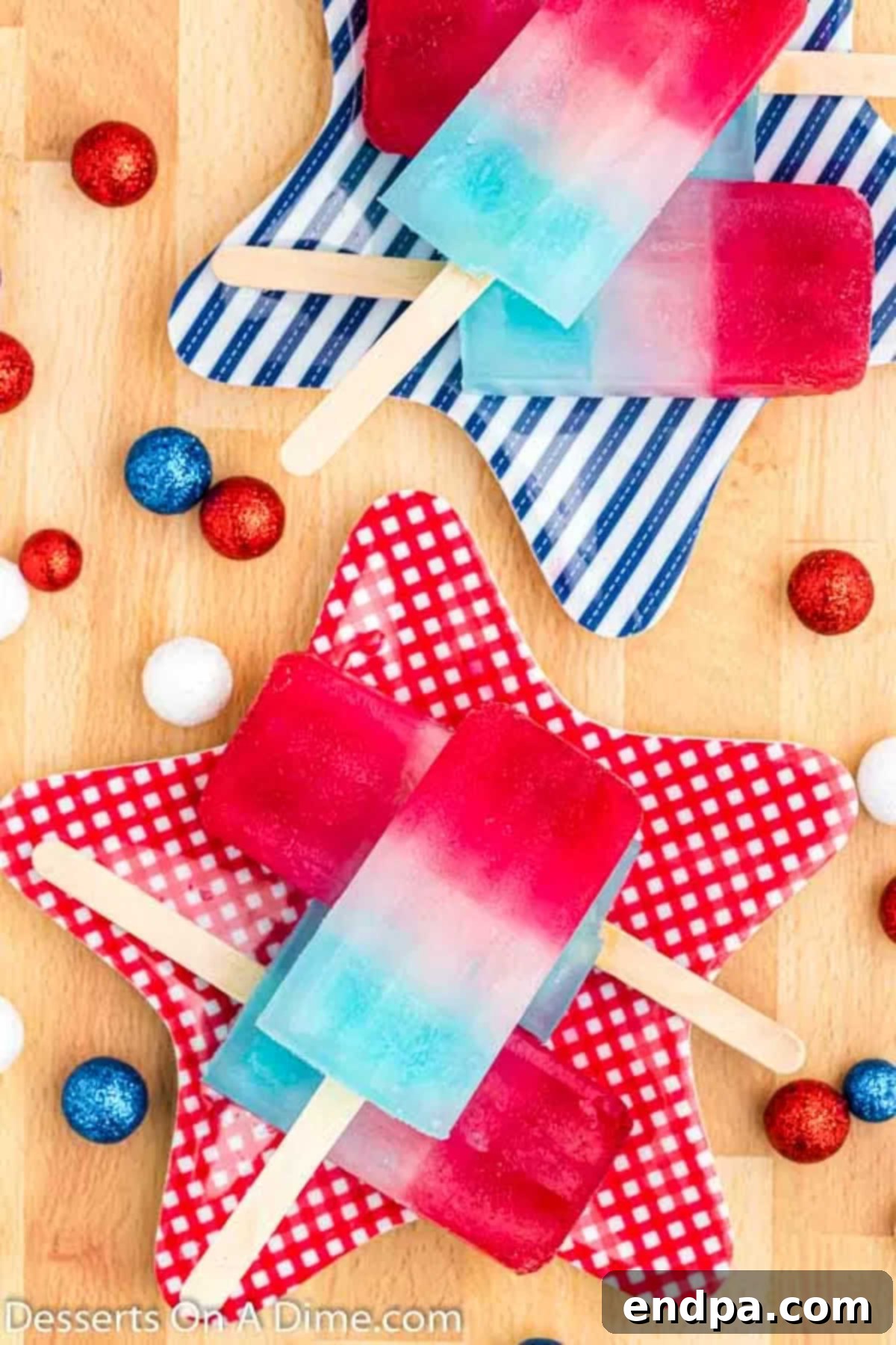 A close-up of beautifully layered red, white, and blue popsicles on a silver tray.