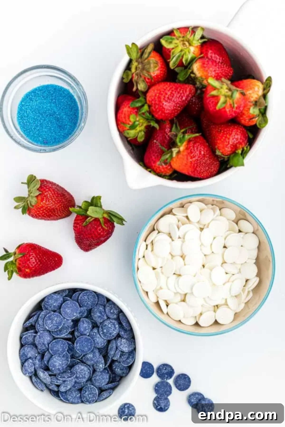 Fresh strawberries, blue sprinkles, and white and blue candy melts laid out as ingredients for patriotic strawberries.