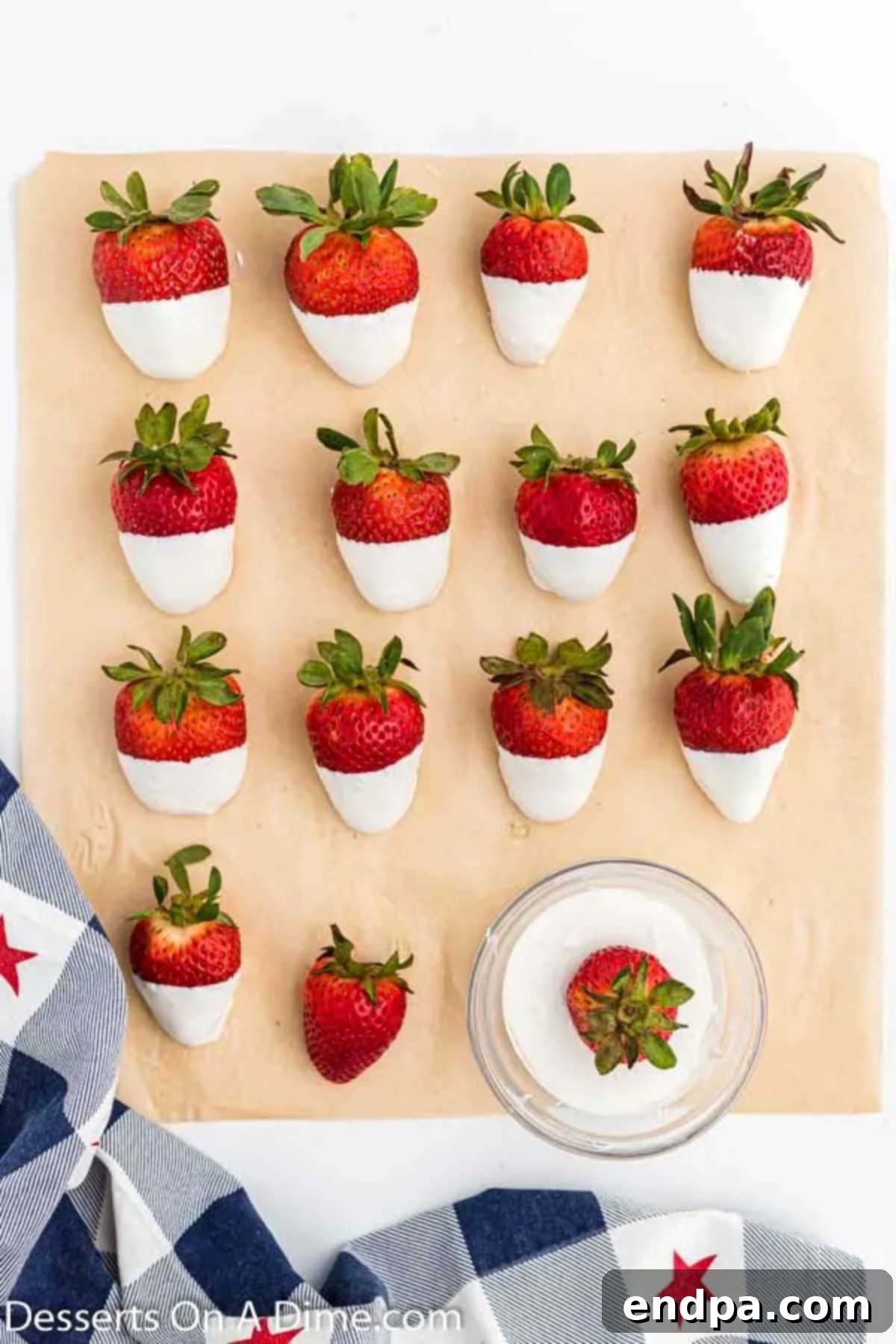 Strawberries dipped halfway in melted white chocolate, resting on parchment paper.