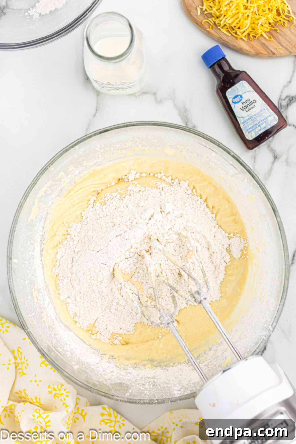 Sunshine Lemon Cake 6 Flour mixture being added to the wet ingredients in a mixing bowl.