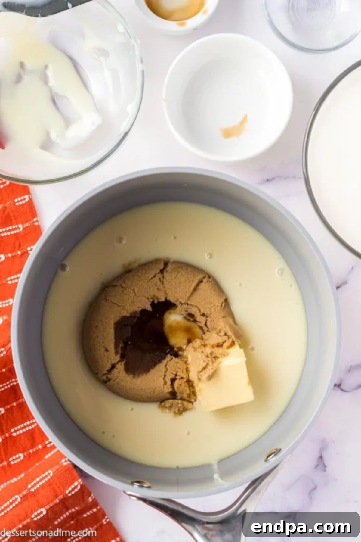 Small saucepan containing butter, brown sugar, vanilla extract, and a portion of heavy whipping cream, ready to be whisked into a butterscotch sauce.