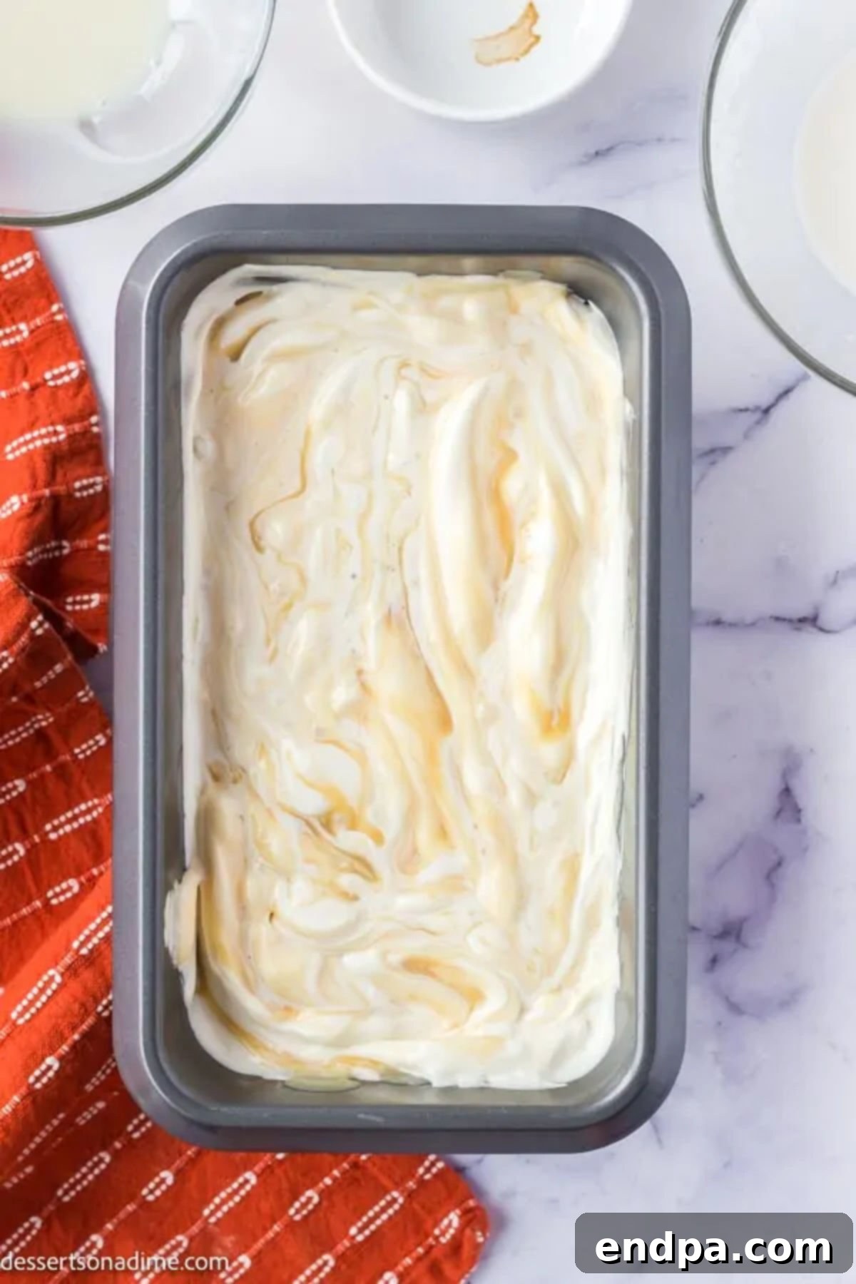 Loaf pan filled with the Butterbeer ice cream mixture, with a swirl of butterscotch sauce on top, ready for freezing.