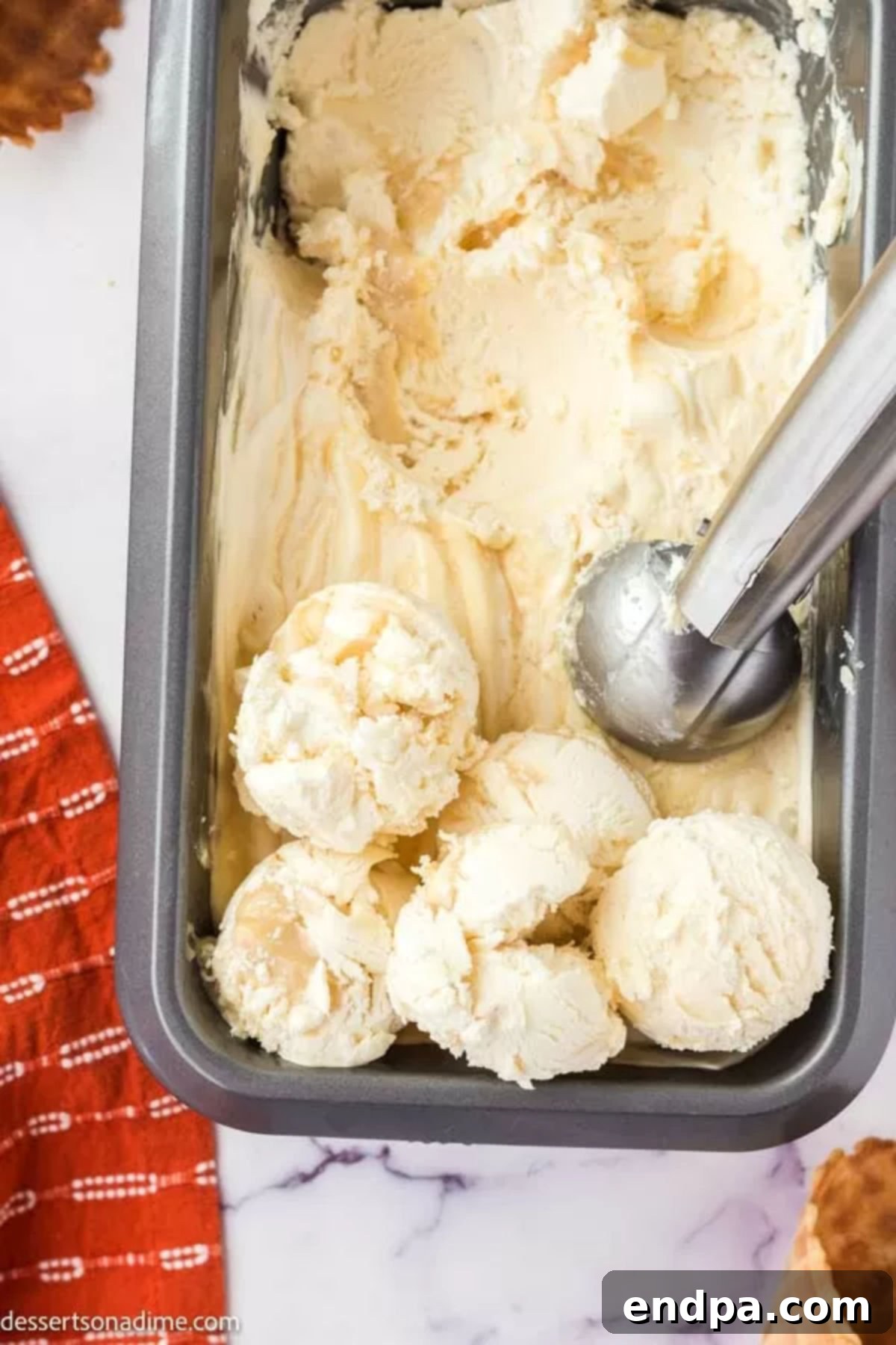 Scoop of frozen Butterbeer ice cream being lifted from a loaf pan, showing its creamy texture.