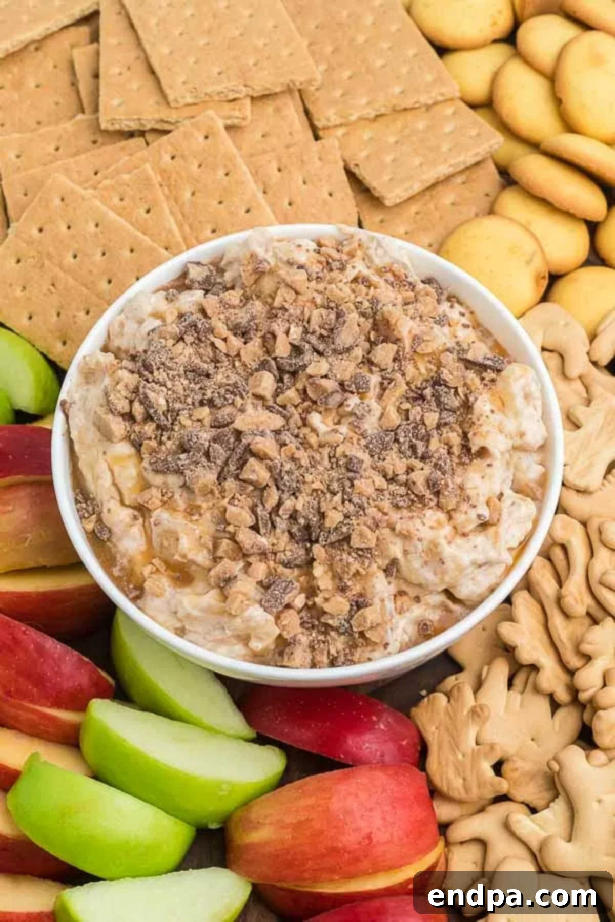 A full bowl of caramel apple cheesecake dip with various dippers.