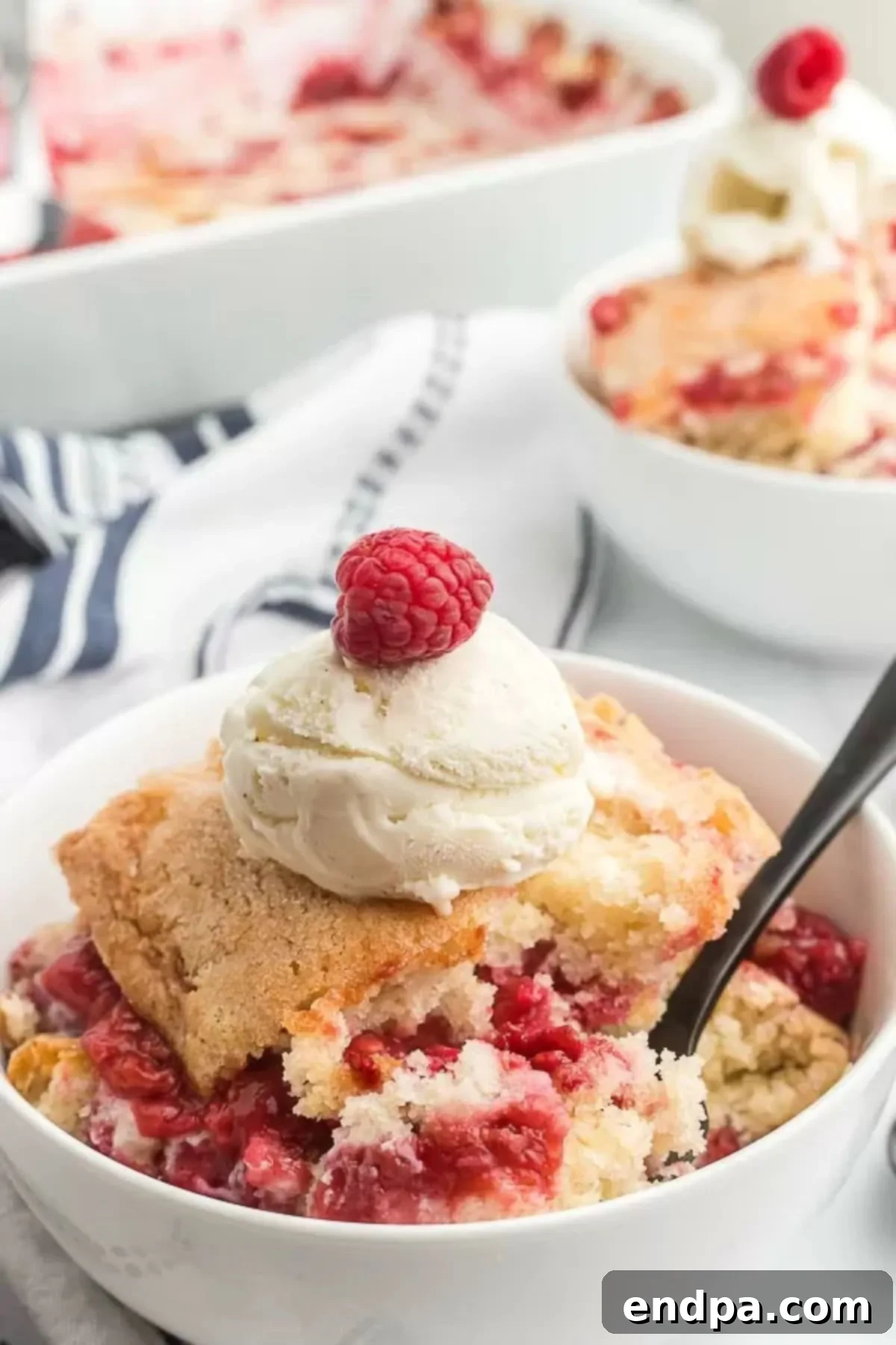 A bowl of raspberry cobbler topped with ice cream, ready to be enjoyed.