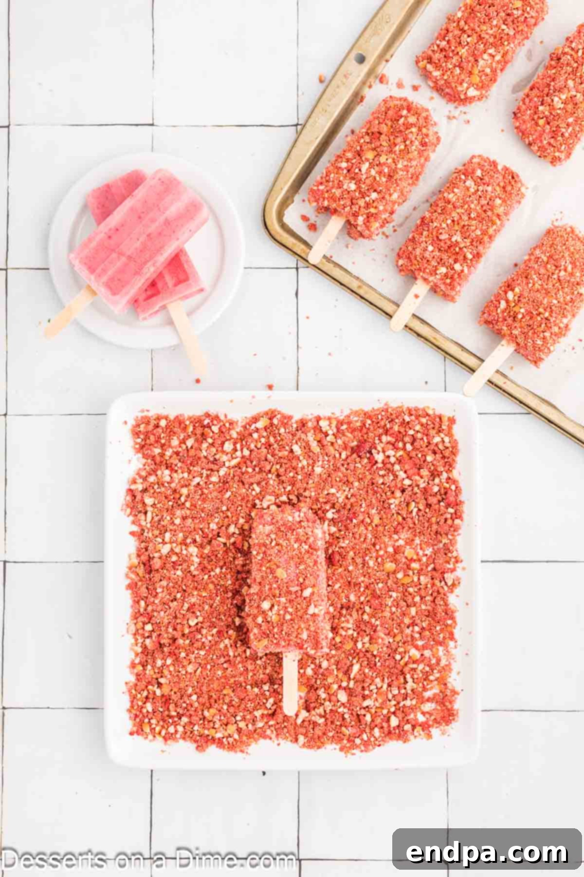 Hand dipping a frozen strawberry shortcake popsicle into the pink crumb coating mixture.