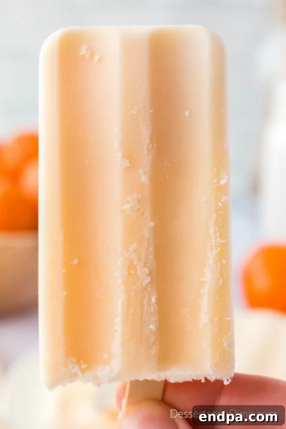 A perfectly frozen Orange Julius popsicle, ready to be eaten, with a slight frost.