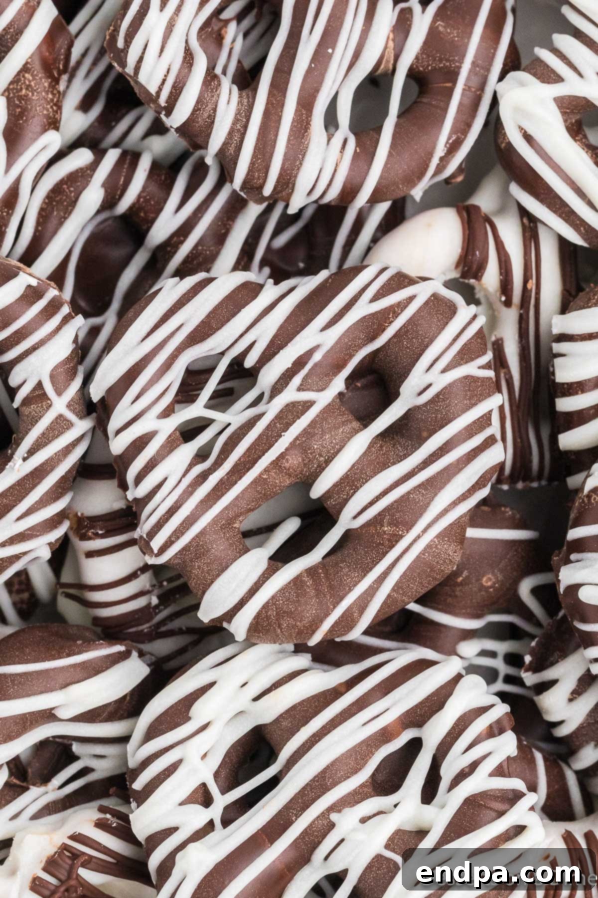 A delightful pile of freshly made chocolate covered pretzels, showcasing various chocolate types and drizzles.
