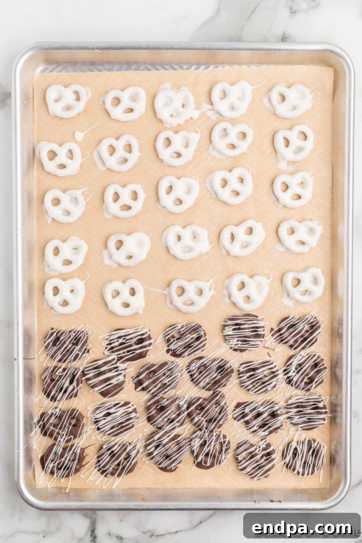 The baking sheet filled with beautifully decorated chocolate covered pretzels, now ready to set.