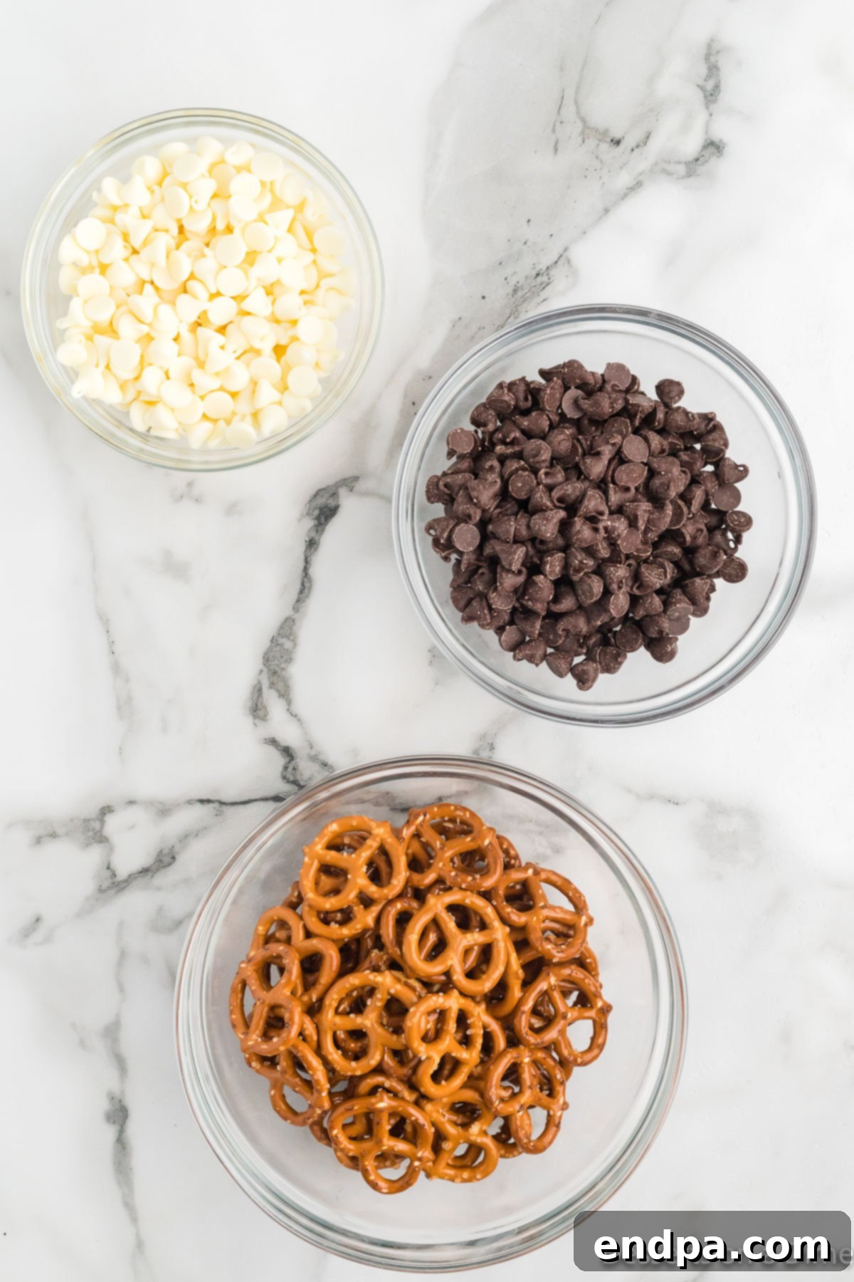 Close-up of ingredients for chocolate covered pretzels: miniature pretzel twists and chocolate chips.