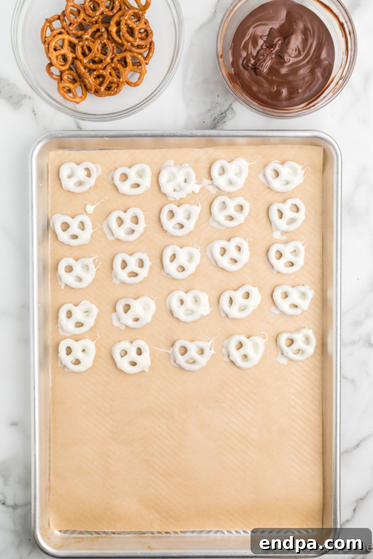 White chocolate covered pretzels laid out neatly on a baking sheet lined with parchment paper.