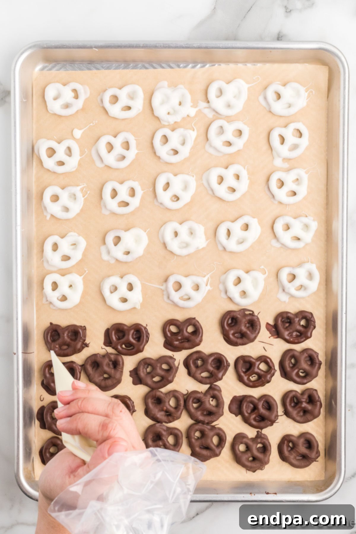 A close-up shot of pretzels being drizzled with a contrasting color of chocolate for decoration.