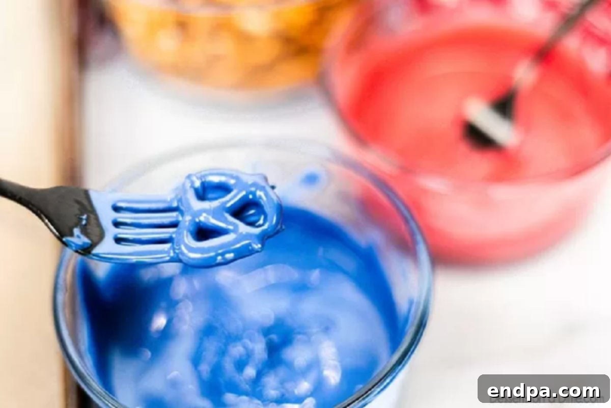 Pretzel being dipped into melted candy melts.