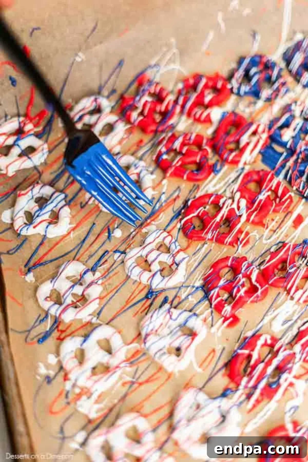 Pretzels on baking sheet drizzled with contrasting colors of candy melts.