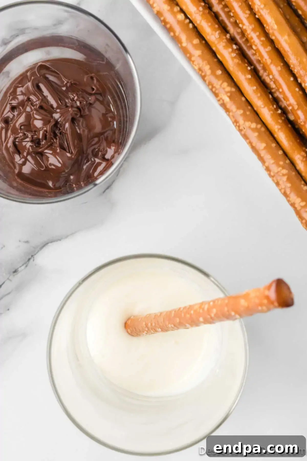 Cup with melted white chocolate and pretzel rod.