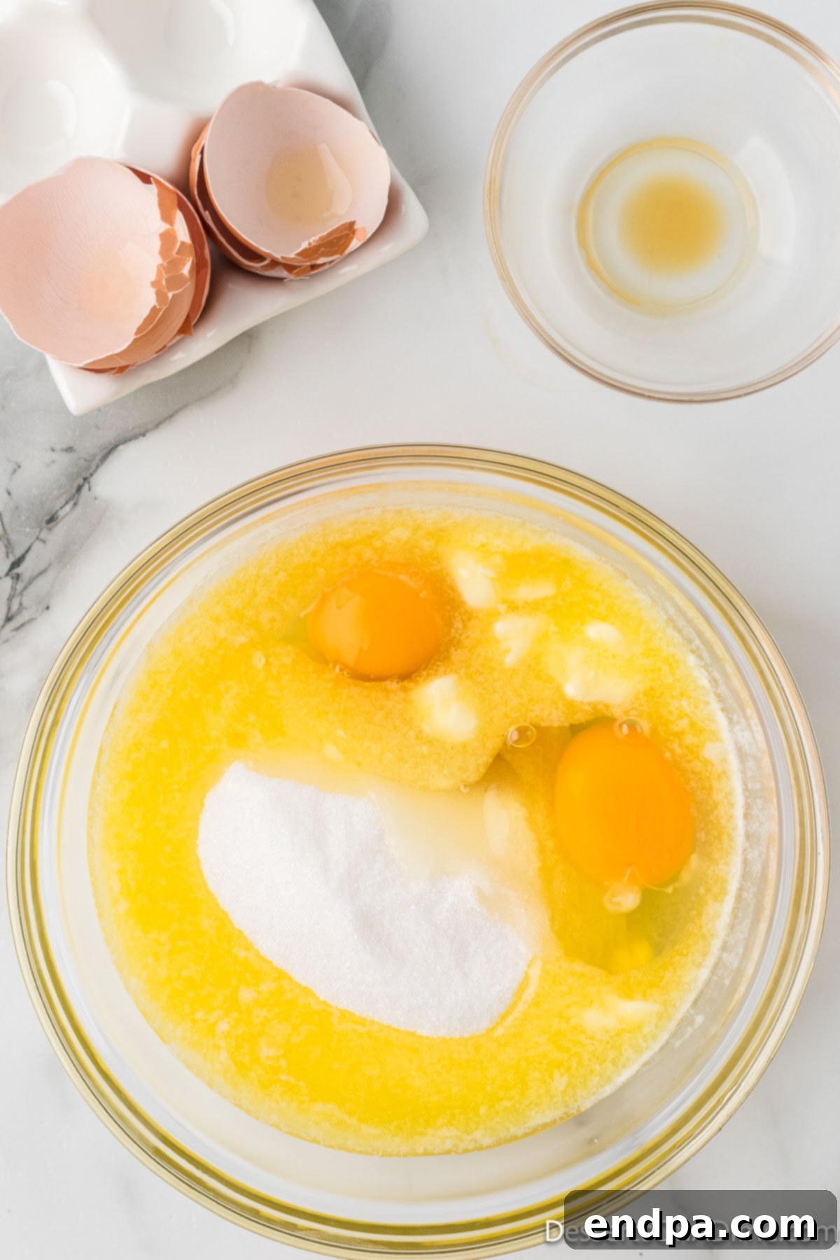 Bite-Sized Brownie Delights 2 Mixing bowl with a golden mixture of eggs, sugar, and vanilla extract being whisked to a light, airy consistency.