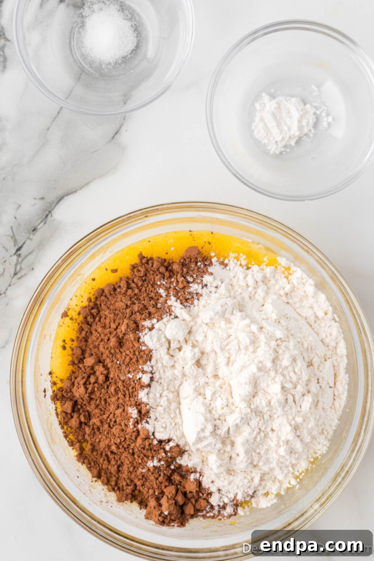 Bite-Sized Brownie Delights 3 Dry ingredients, including cocoa powder and flour, being gently folded into the wet mixture in a mixing bowl to form a smooth chocolate brownie batter.