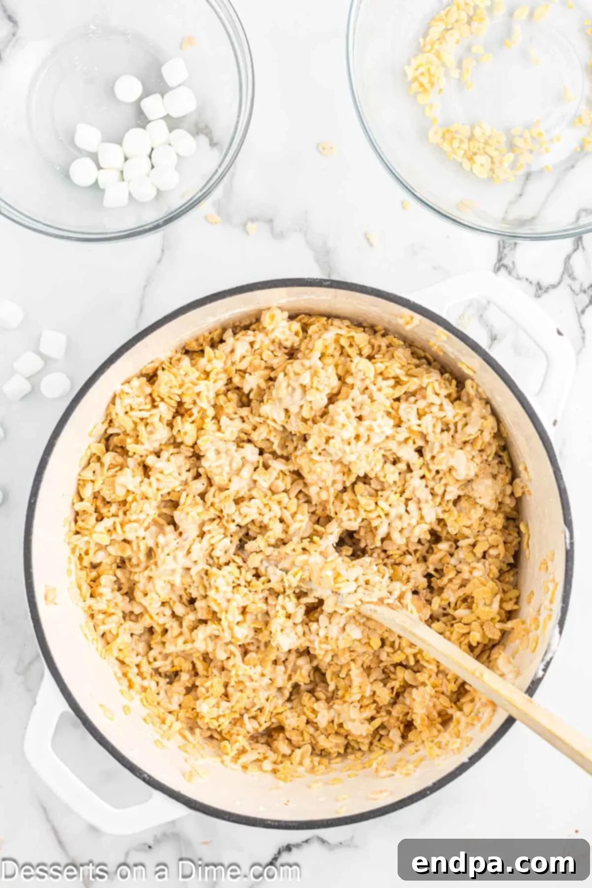 Crispy Marshmallow Bars 8 The crispy rice cereal fully combined with the marshmallow mixture, forming a sticky, cohesive mass in the saucepan.