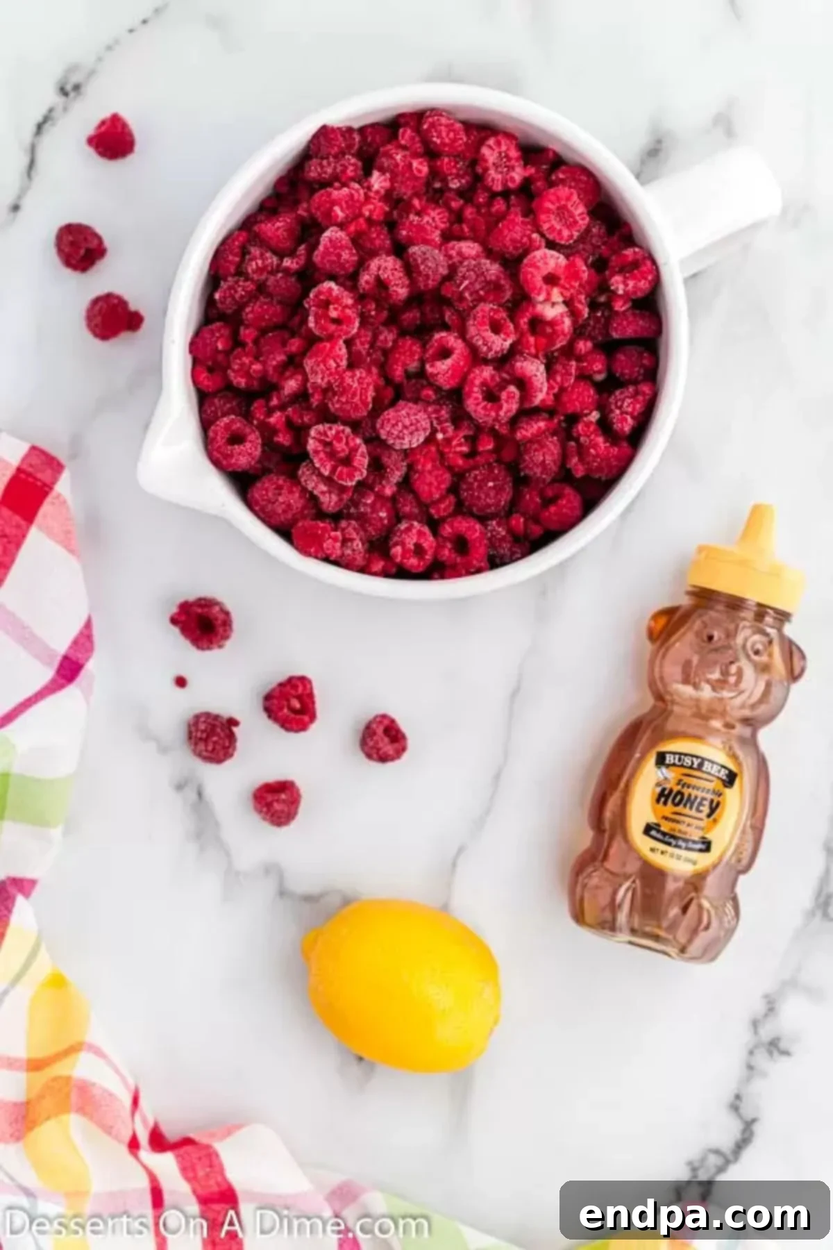 Tangy Raspberry Delight 3 Fresh and frozen raspberries, a jar of honey, and a bright yellow lemon are displayed, representing the core ingredients for Raspberry Sorbet.