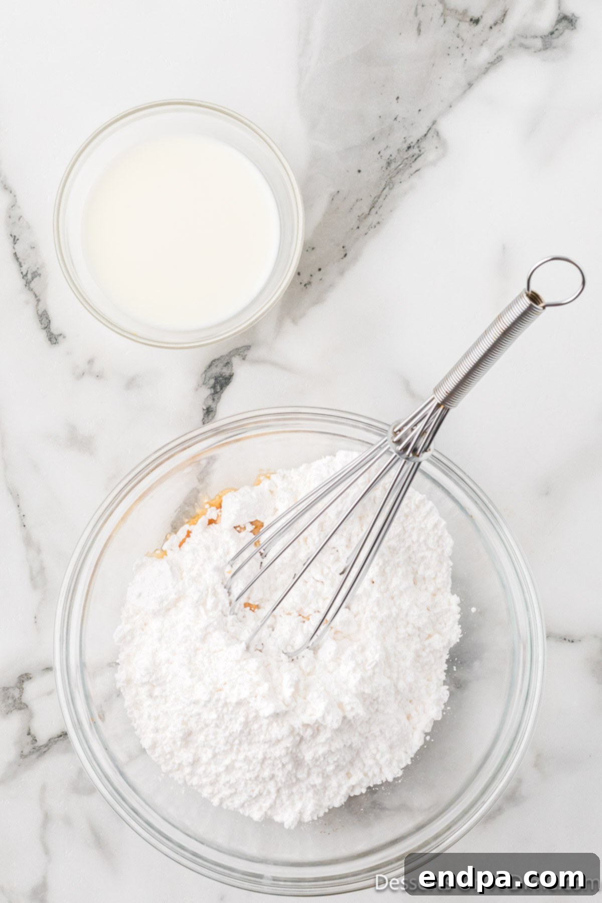 Ingredients for the sweet vanilla glaze being whisked together in a bowl, creating a smooth, pourable consistency.