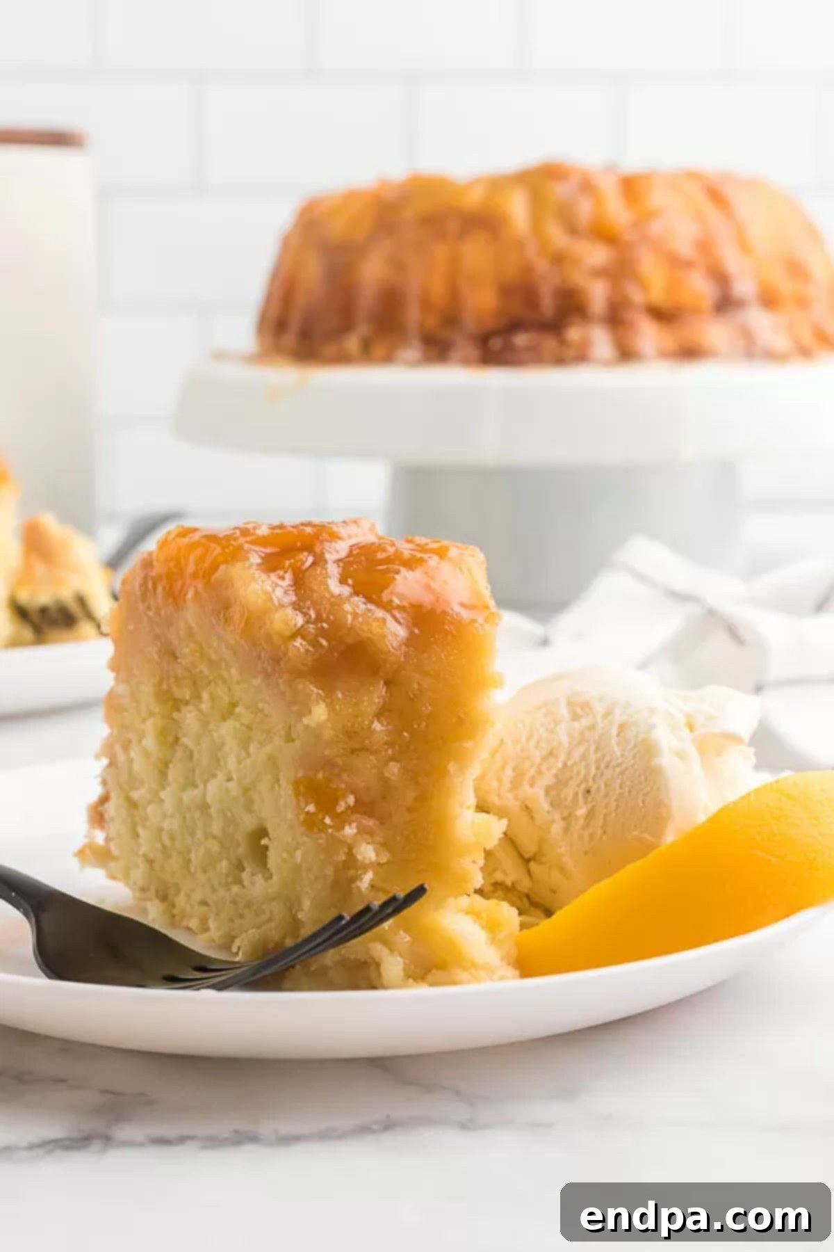 A delectable slice of Peach Cobbler Pound Cake served on a plate with a scoop of vanilla ice cream, showcasing its tender texture.