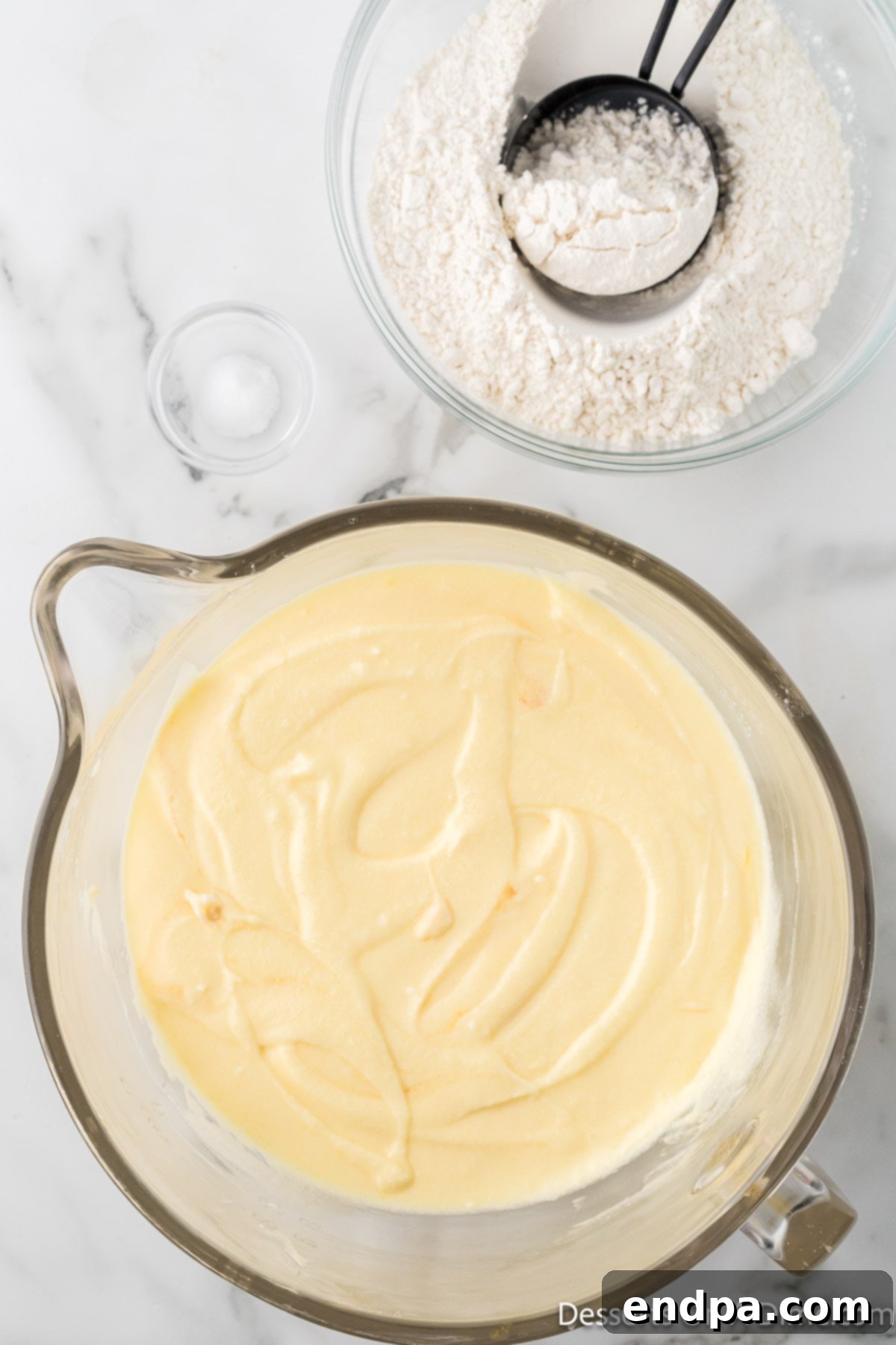 Creamy cake batter being mixed in a large bowl, showcasing its smooth and light consistency.